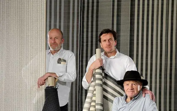 Drie wevers met rollen stof. Stoffen van Bisson - Bruneel.