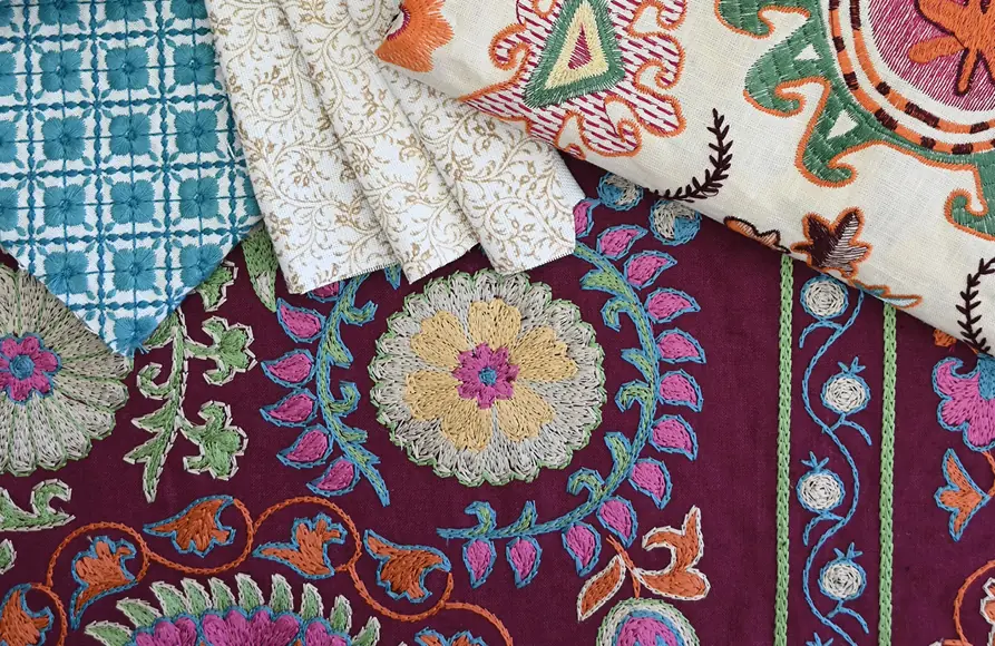 Geborduurde stoffen in paars en blauw over elkaar. Stoffen van Brunschwig & Fils.