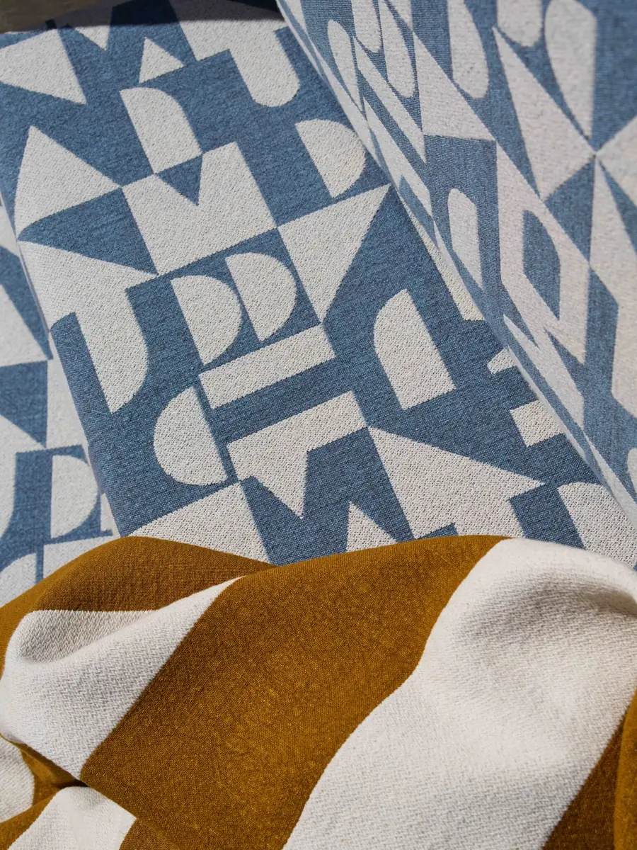 Abstract dessin in blauw en oker gedrapeerd over een marmerblok. Stoffen van Decortex Firenze.