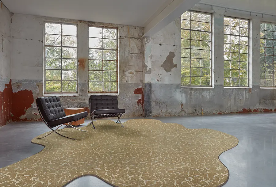 Karpet met organische vorm in okertinten in een ruwe ruimte. Tapijt van Edel Carpets.