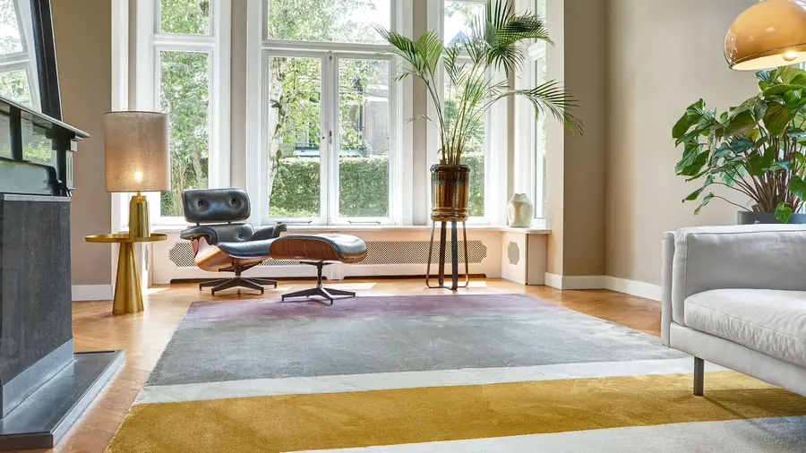 Woonkamer met loungestoel op een geel en grijs karpet. Tapijt van Edel Carpets.