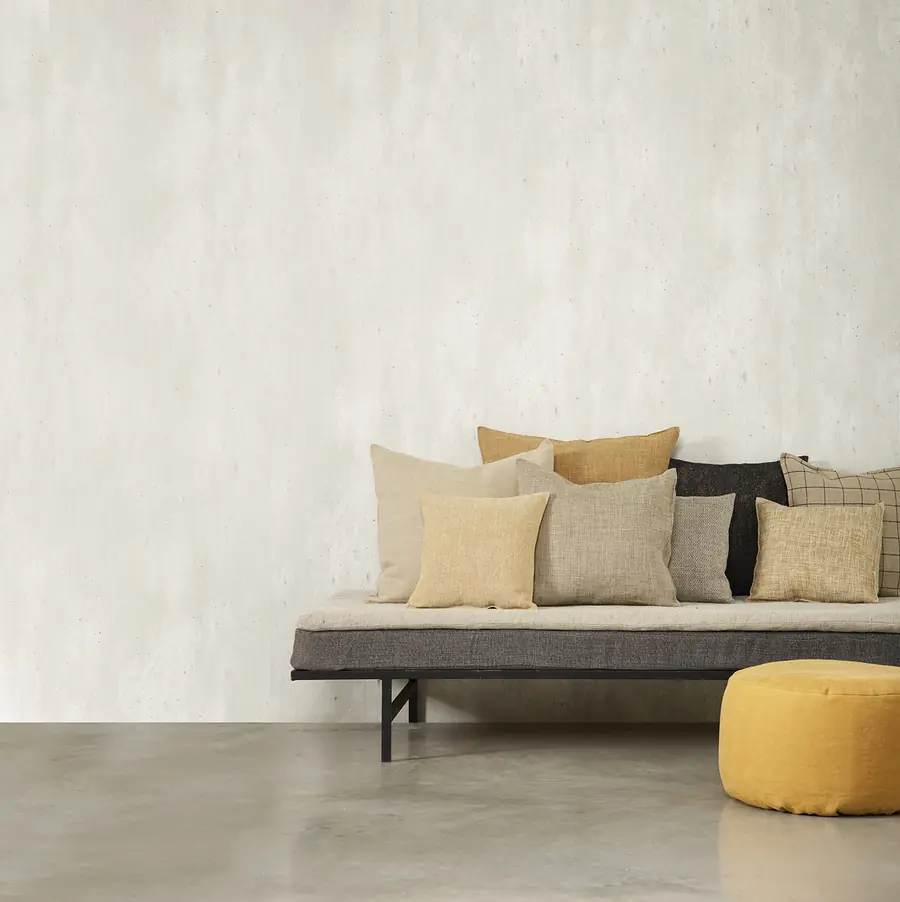 Daybed met linnen kussens tegen een leemwand. Stoffen van Libeco.