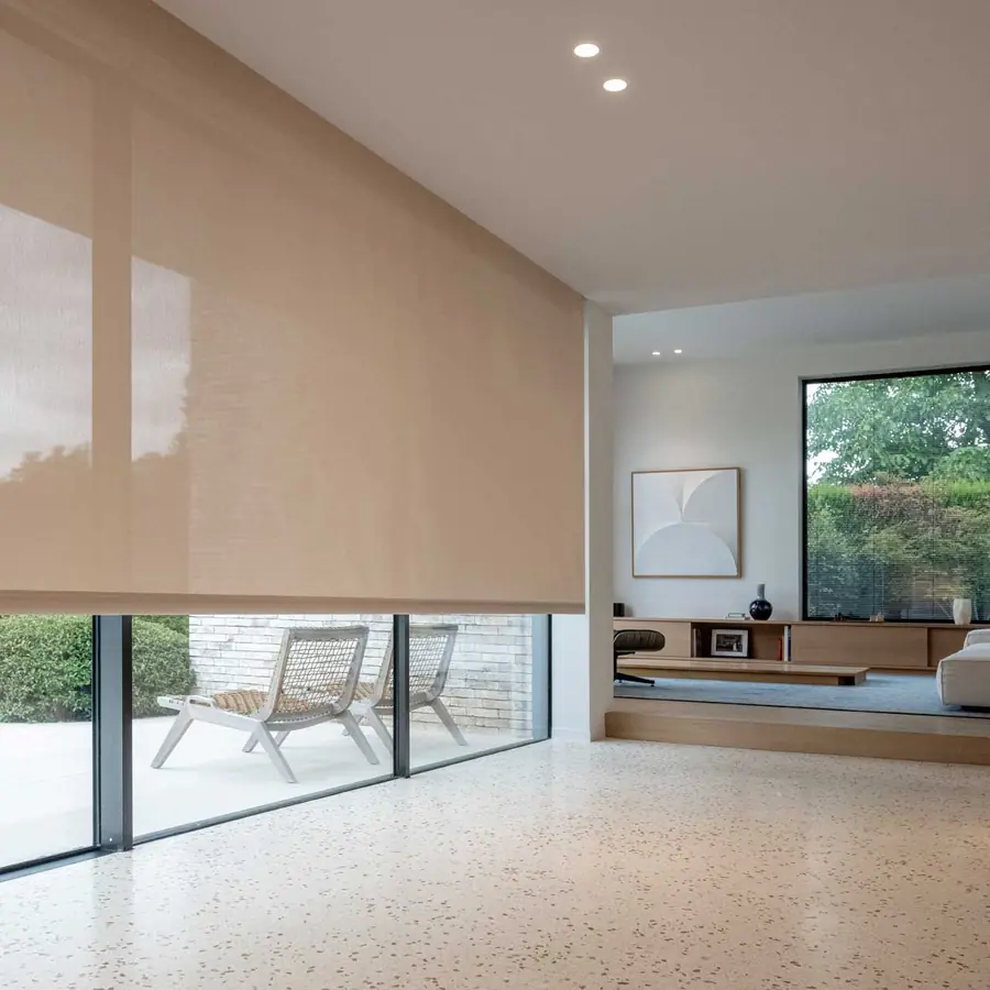 Woonkamer met terracotta rolgordijn en tuinzicht. Zonwering van Louverdrape.