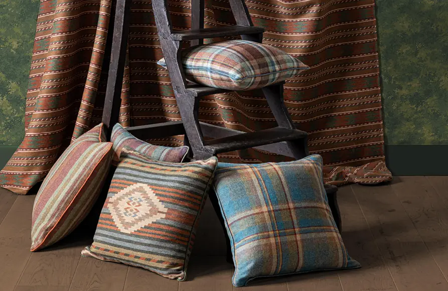 Wollen ruitstoffen en kussens op een houten ladder. Stoffen van Mulberry Home.