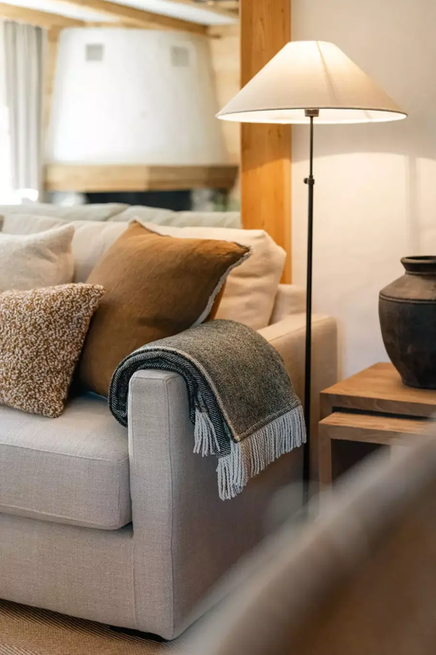 Salon met lichtgrijze zetel, plaid en schemerlamp. Meubelen van Scapa Home.