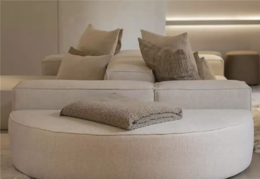 Zithoek met beige zetel en kussens in natuurtinten. Meubelen van Scapa Home.